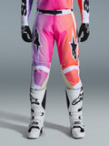 Alpinestars 2026 Racer Air Portl Pants, calças de motocross, gradiente vibrante de roxo, rosa e cor-de-laranja, com logótipos de estrela em destaque nas coxas, usadas com botas de corrida brancas e luvas pretas, concebidas para condução todo-o-terreno de alto desempenho.