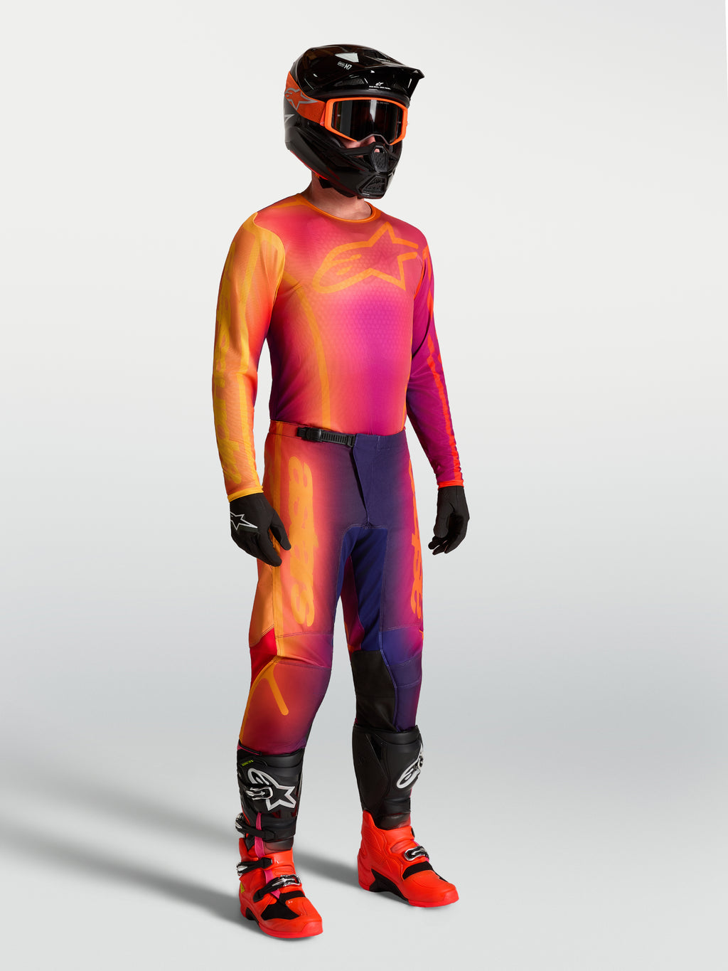 Camisola Fluid Kepler da Alpinestars, camisola de motocross roxa e laranja num modelo com equipamento de corrida a condizer.