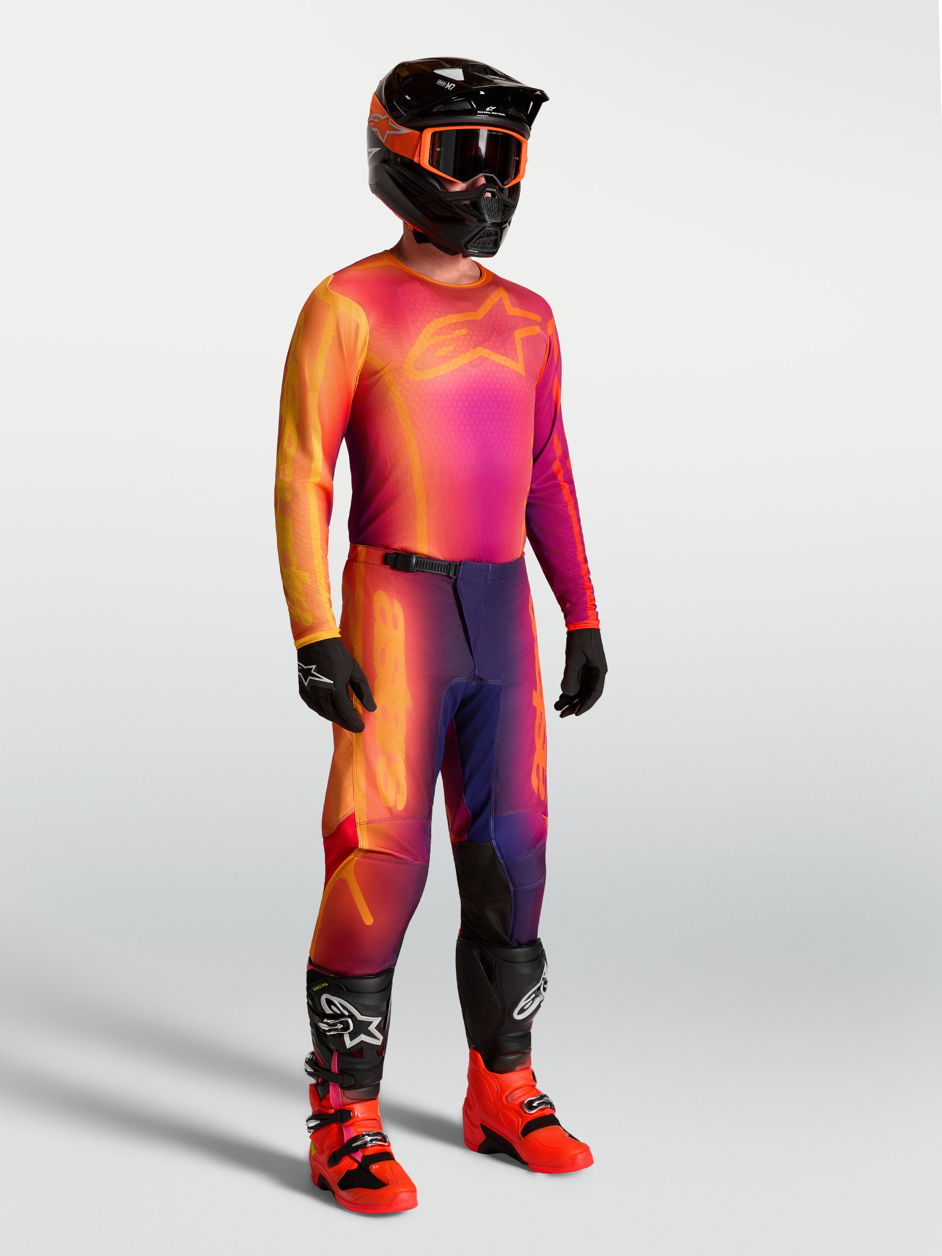 Camisola Fluid Kepler da Alpinestars, camisola de motocross roxa e laranja num modelo com equipamento de corrida a condizer.