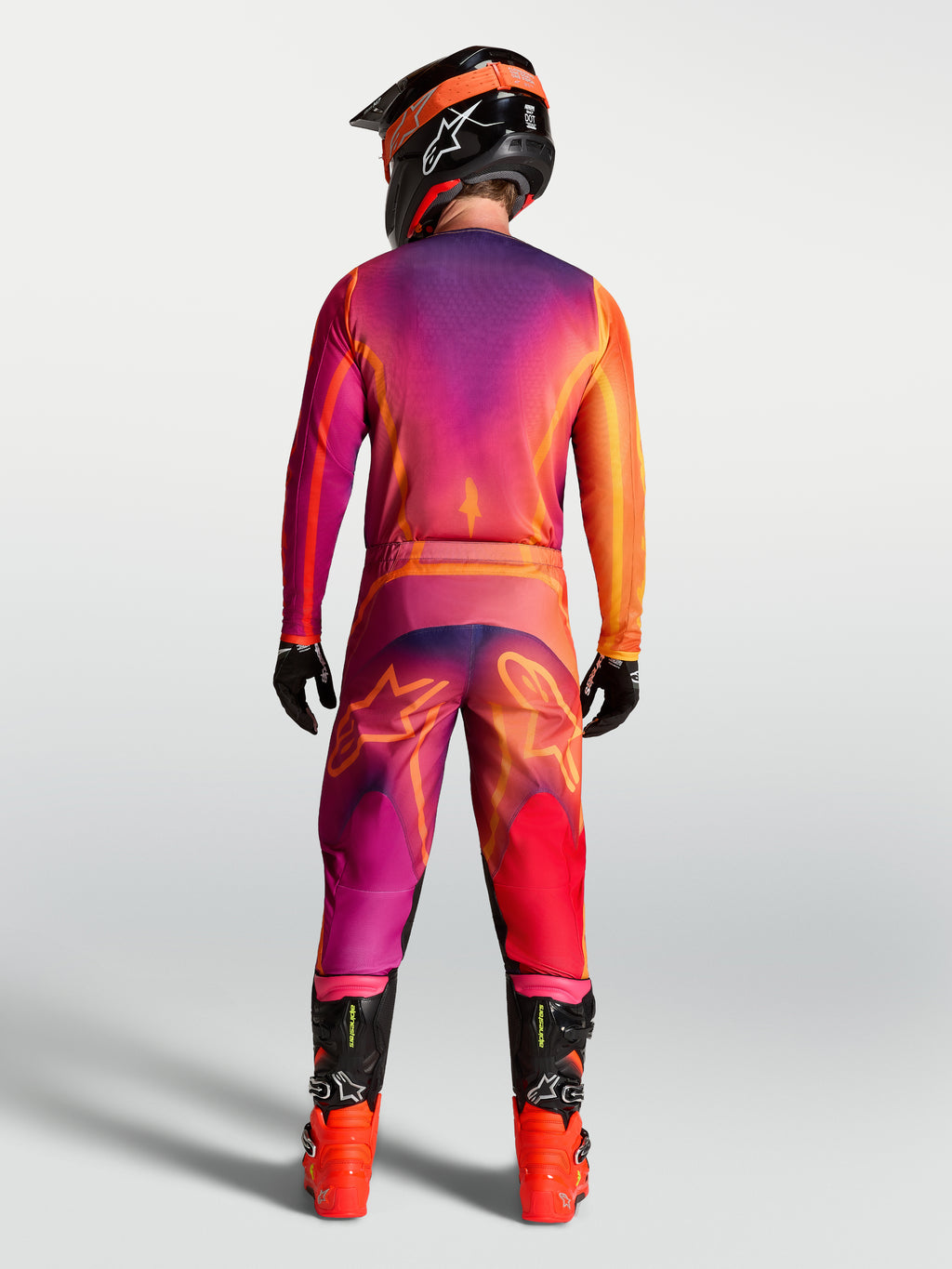 Alpinestars Camisola Fluid Kepler, camisola de motocross para homem, roxa e laranja, vista traseira do piloto com calças e equipamento de todo-o-terreno a condizer.