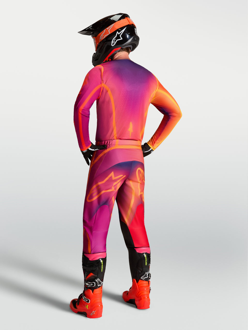 Alpinestars camisola Fluid Kepler, camisola de motocross roxa e laranja, vista traseira num piloto para condução off-road.