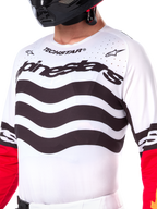 Alpinestars Limited Edition Techstar Deep Jersey, white motocross jersey with wavy black horizontal stripes and red sleeves, featuring Alpinestars and Techstar branding, small laser-cut perforations on the upper chest for ventilation, athletic off-road gear