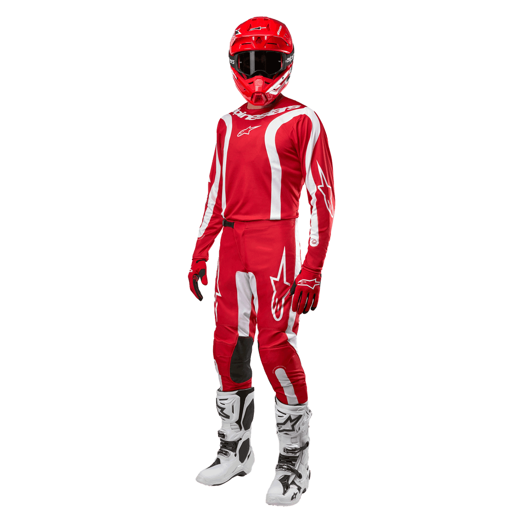 Piloto de motocross com equipamento completo, camisola Alpinestars 2024 Fluid Lurv em Vermelho Mars e Branco, calças vermelhas com detalhes brancos a condizer, capacete vermelho, luvas vermelhas e botas brancas e pretas, conjunto coordenado para corridas de todo-o-terreno