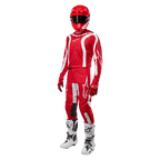 Piloto de motocross com equipamento completo, camisola Alpinestars 2024 Fluid Lurv em Vermelho Mars e Branco, calças vermelhas com detalhes brancos a condizer, capacete vermelho, luvas vermelhas e botas brancas e pretas, conjunto coordenado para corridas de todo-o-terreno