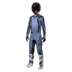 Piloto de motocross com equipamento de competição completo, camisola Alpinestars 2024 Fluid Lurv em azul claro e preto, calças em azul claro a condizer com painéis pretos, botas brancas e pretas, luvas pretas e capacete preto com óculos, conjunto coordenado para corridas todo-o-terreno