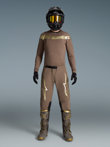 Conjunto Supertech Air Gold Edição Limitada, equipamento de motocross bege com logótipos ouro metálico, botas e capacete.