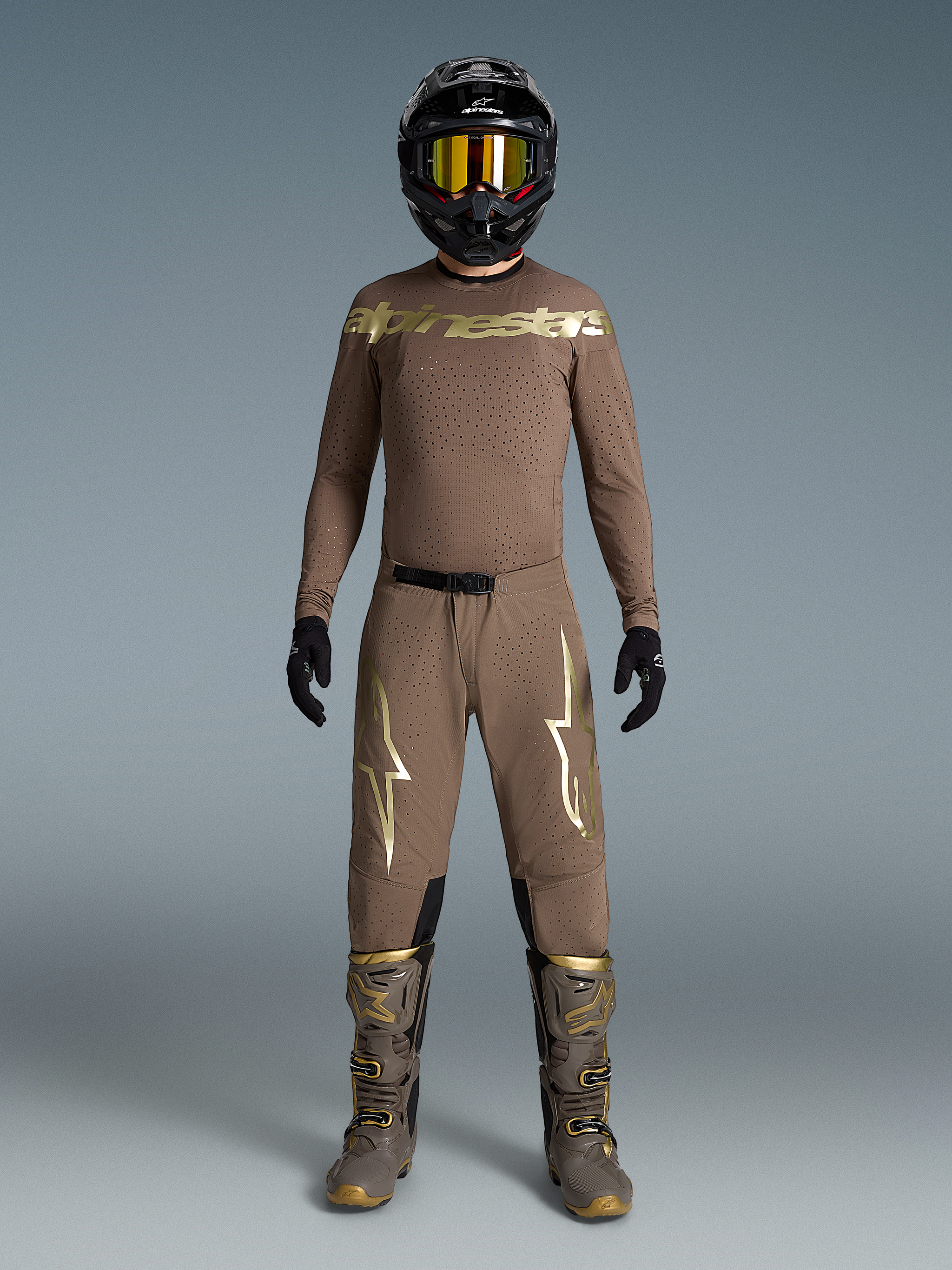 Conjunto Supertech Air Gold Edição Limitada, equipamento de motocross bege com logótipos ouro metálico, botas e capacete.