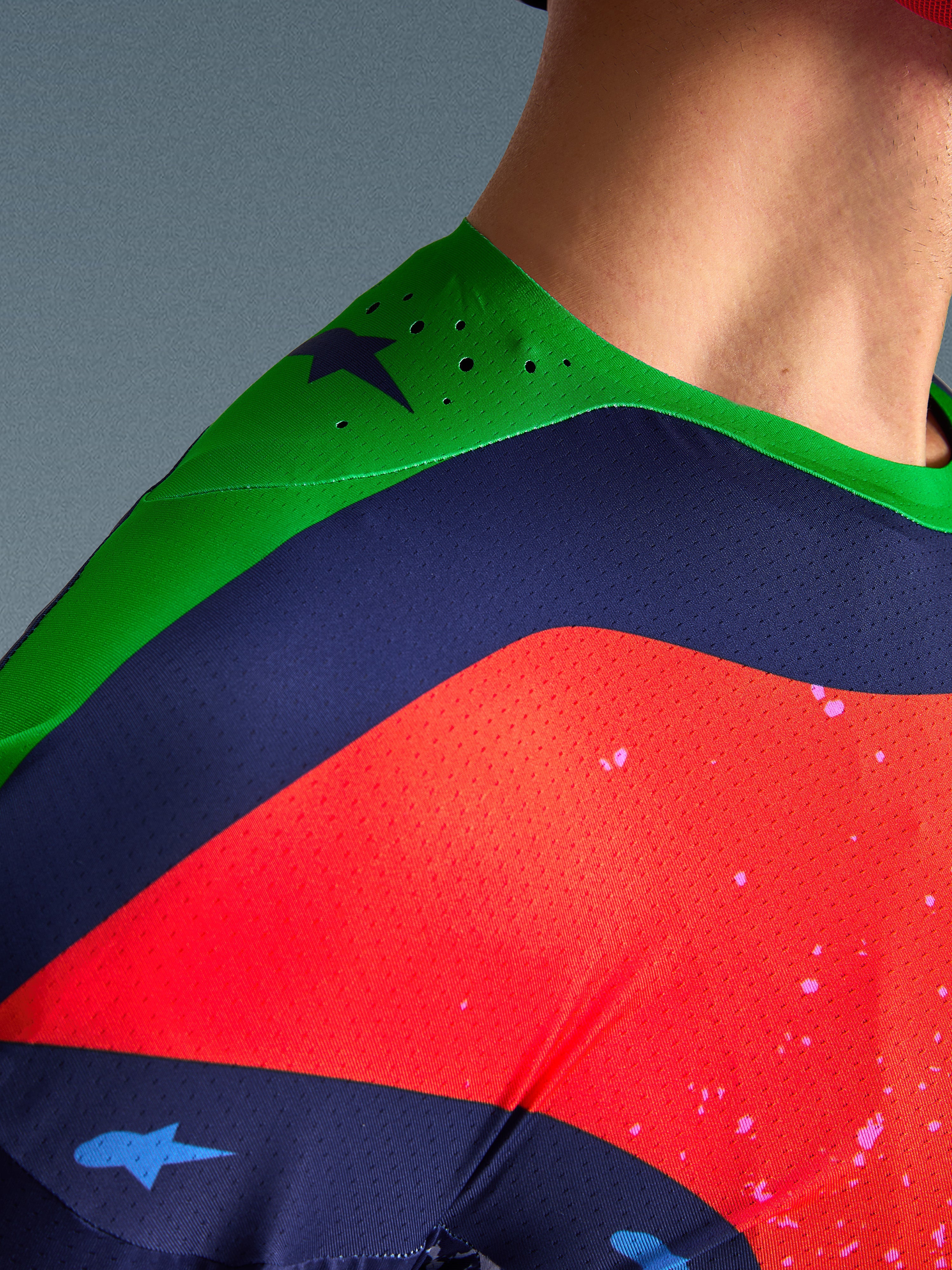 Close-up of the Alpinestars Limited Edition Supertech Records Jersey, multicolor design with green shoulder, navy and red panels, featuring laser-cut perforations and breathable mesh fabric for professional motocross performance.