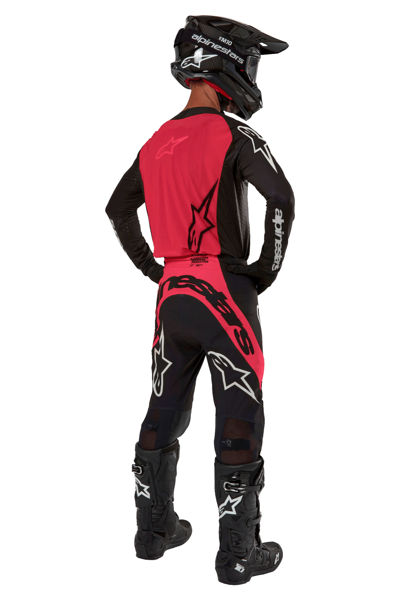 Piloto de motocross visto de costas a usar a camisola 2024 Supertech Ward em Black Red Berry, com um painel traseiro vermelho vibrante e mangas pretas com a marca Alpinestars a branco. Combinado com calças de motocross a condizer, botas Tech 10 pretas e um capacete de fibra de carbono preto para um conjunto de equipamento de corrida profissional coordenado.