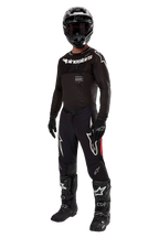 Piloto de motocross com equipamento de corrida completo, Camisola Supertech Ward 2024 em Preto Vermelho, camisola preta com logótipo Alpinestars branco, calças pretas com painéis laterais vermelhos e grandes logótipos Astars brancos, capacete, luvas e botas pretas, conjunto de nível profissional para corridas de todo-o-terreno