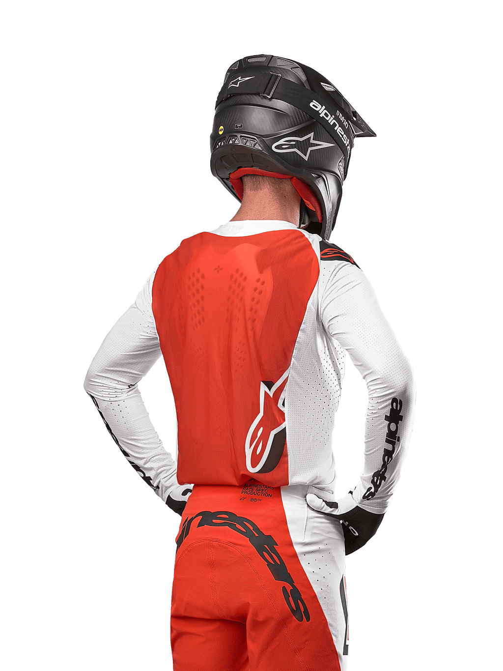 Camisola Alpinestars Supertech Ward 2024 em White Hot Orange, vista traseira de um piloto de motocross, painel traseiro laranja e mangas brancas com logótipo preto, calças a condizer e capacete preto, equipamento profissional para off-road