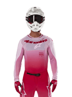 Piloto de motocross a usar a camisola Alpinestars 2024 Supertech Dade em Red Berry Lilac, calças a condizer, capacete branco com óculos pretos e luvas vermelhas, equipamento de corrida profissional coordenado com tons degradê em rosa e vermelho