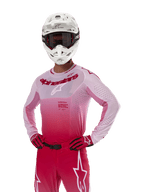 Alpinestars 2024 Supertech Dade Jersey, equipamento de motocross, design com gradiente Red Berry Lilac, camisola de manga comprida com perfurações cortadas a laser, usada por um piloto com capacete branco e luvas e calças vermelhas a condizer, kit profissional de motocross sobre fundo branco