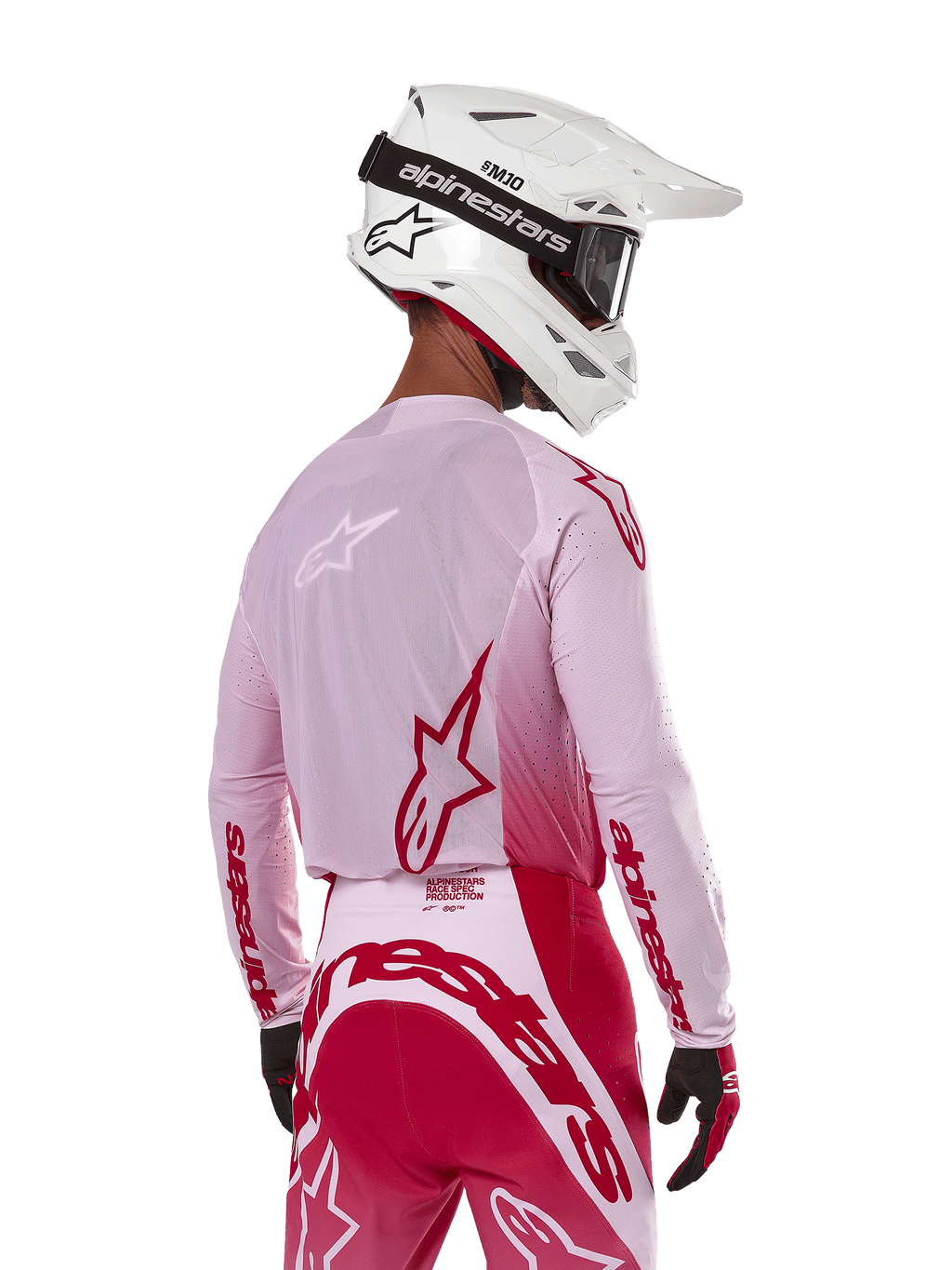 Piloto de motocross visto de costas a usar a camisola Alpinestars 2024 Supertech Dade em Red Berry Lilac, com painéis em malha respirável e logótipos Alpinestars vermelhos, combinada com calças em vermelho e lilás a condizer e um capacete Alpinestars branco com óculos, equipamento profissional de corrida todo-o-terreno