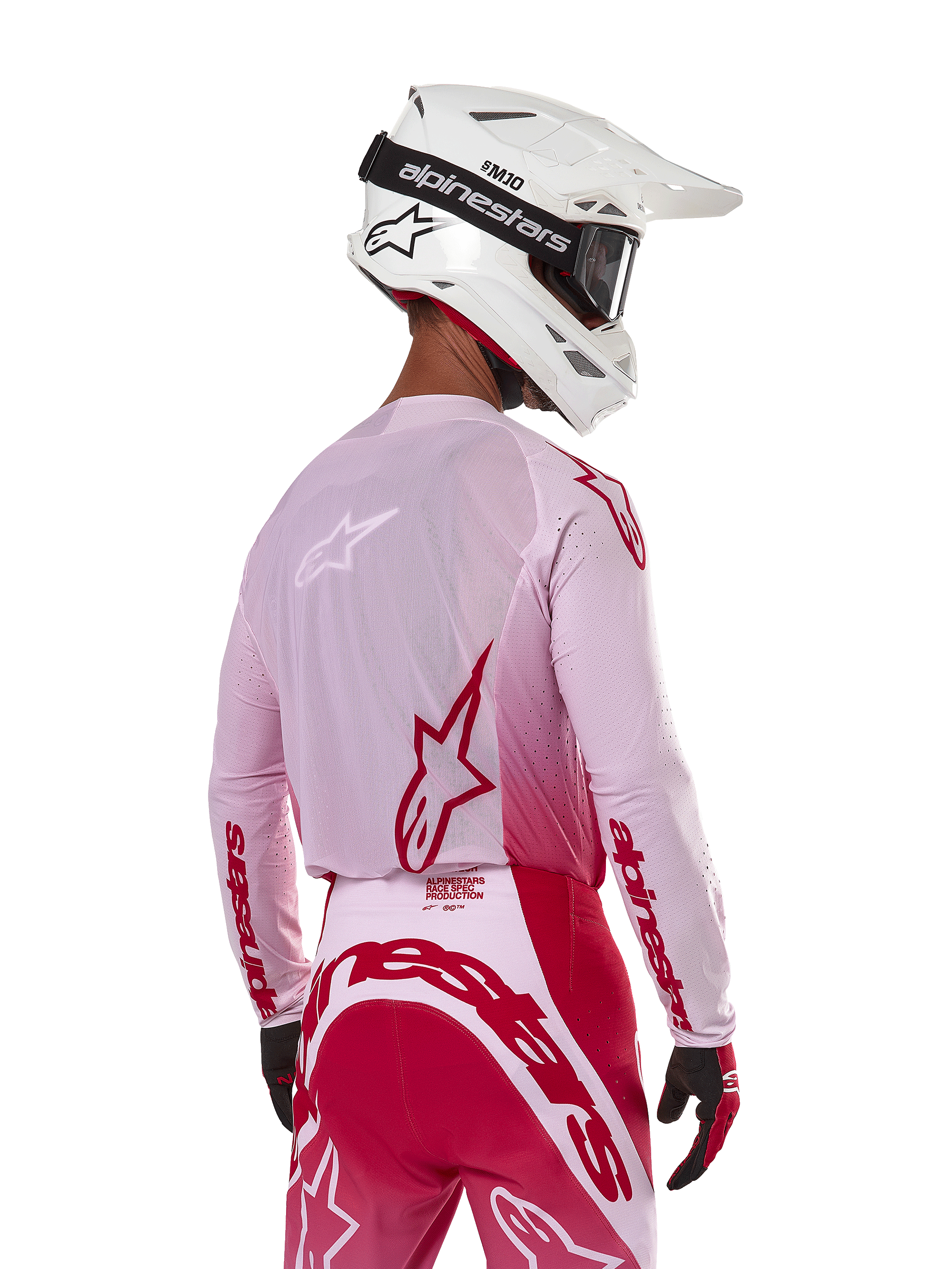Piloto de motocross visto de costas a usar a camisola Alpinestars 2024 Supertech Dade em Red Berry Lilac, com painéis em malha respirável e logótipos Alpinestars vermelhos, combinada com calças em vermelho e lilás a condizer e um capacete Alpinestars branco com óculos, equipamento profissional de corrida todo-o-terreno