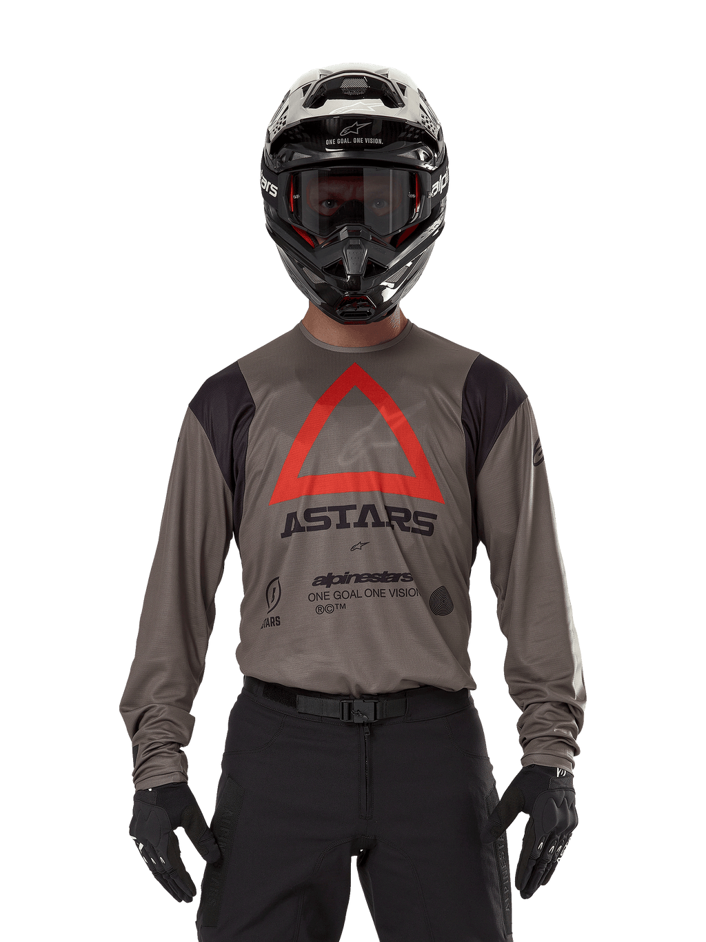 Piloto de motocross a usar a Camisola Alpinestars Techdura em Falcon Brown, com um triângulo vermelho proeminente e a marca 'ASTARS' no peito, acompanhada de calças pretas, capacete preto com óculos e luvas pretas, equipamento completo de corrida enduro