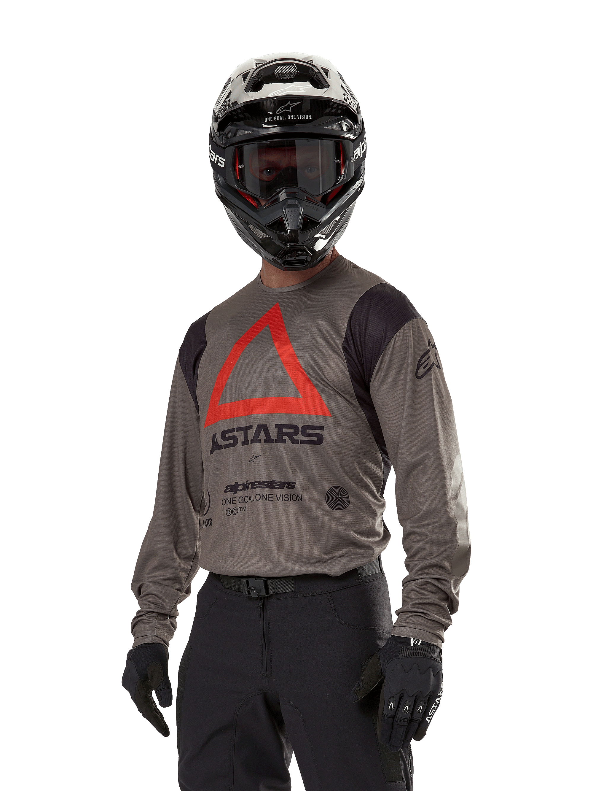 Alpinestars Techdura Jersey, camisola de motocross e todo-o-terreno, castanho Falcon com triângulo vermelho e logótipos pretos, usada com calças pretas, capacete preto e branco e luvas pretas