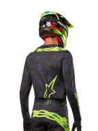 Rear view of a motocross rider wearing the Alpinestars 2024 Techstar Rantera Jersey in Black Navy Yellow Fluo, featuring prominent yellow fluo branding and logos on the back, paired with matching motocross pants and a neon yellow helmet for a complete off-road racing look.