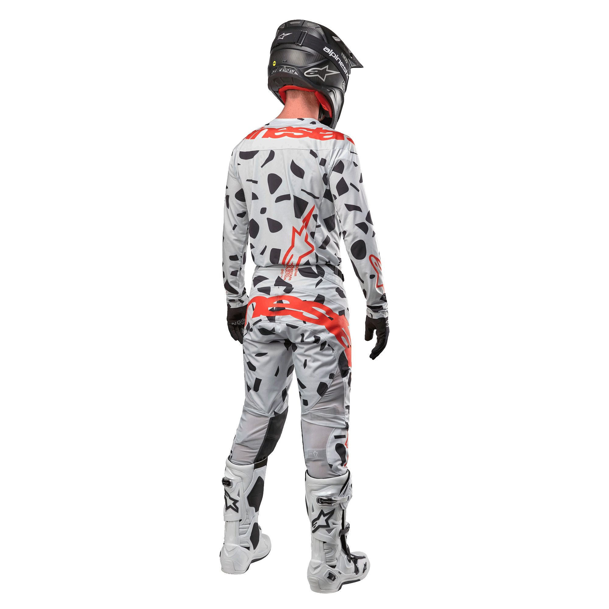 Piloto de motocross visto de costas a usar camisola Alpinestars 2024 Techstar Rantera e calças a condizer, padrão Haze Gray Camo com logótipos Alpinestars vermelhos destacados, capacete preto, botas brancas e pretas, luvas pretas, conjunto de equipamento de motocross coordenado
