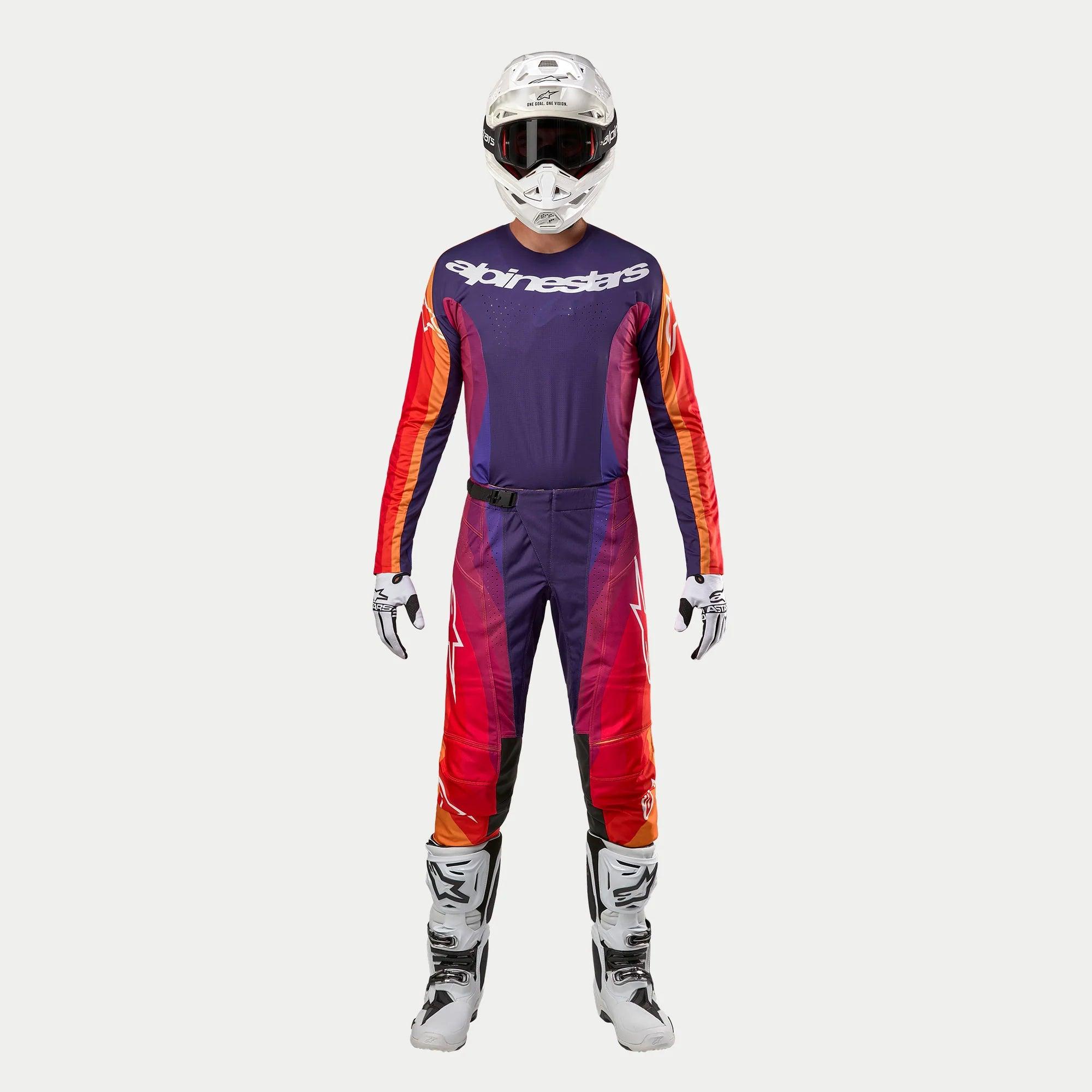 Equipamento completo de motocross Alpinestars 2024 Techstar Pneuma, incluindo capacete branco, camisola e calças em tons de roxo, laranja e azul com o logótipo Alpinestars, luvas brancas e pretas, e botas brancas de proteção.