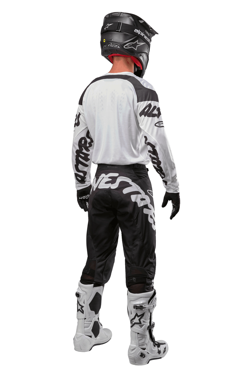Alpinestars 2024 Racer Hana Jersey, vista traseira de piloto de motocross, Branco e Preto, camisola branca com logótipo gráfico preto nas mangas, combinada com calças pretas com letras Alpinestars brancas na zona do assento, capacete preto e botas brancas e pretas, equipamento de corrida todo-o-terreno coordenado