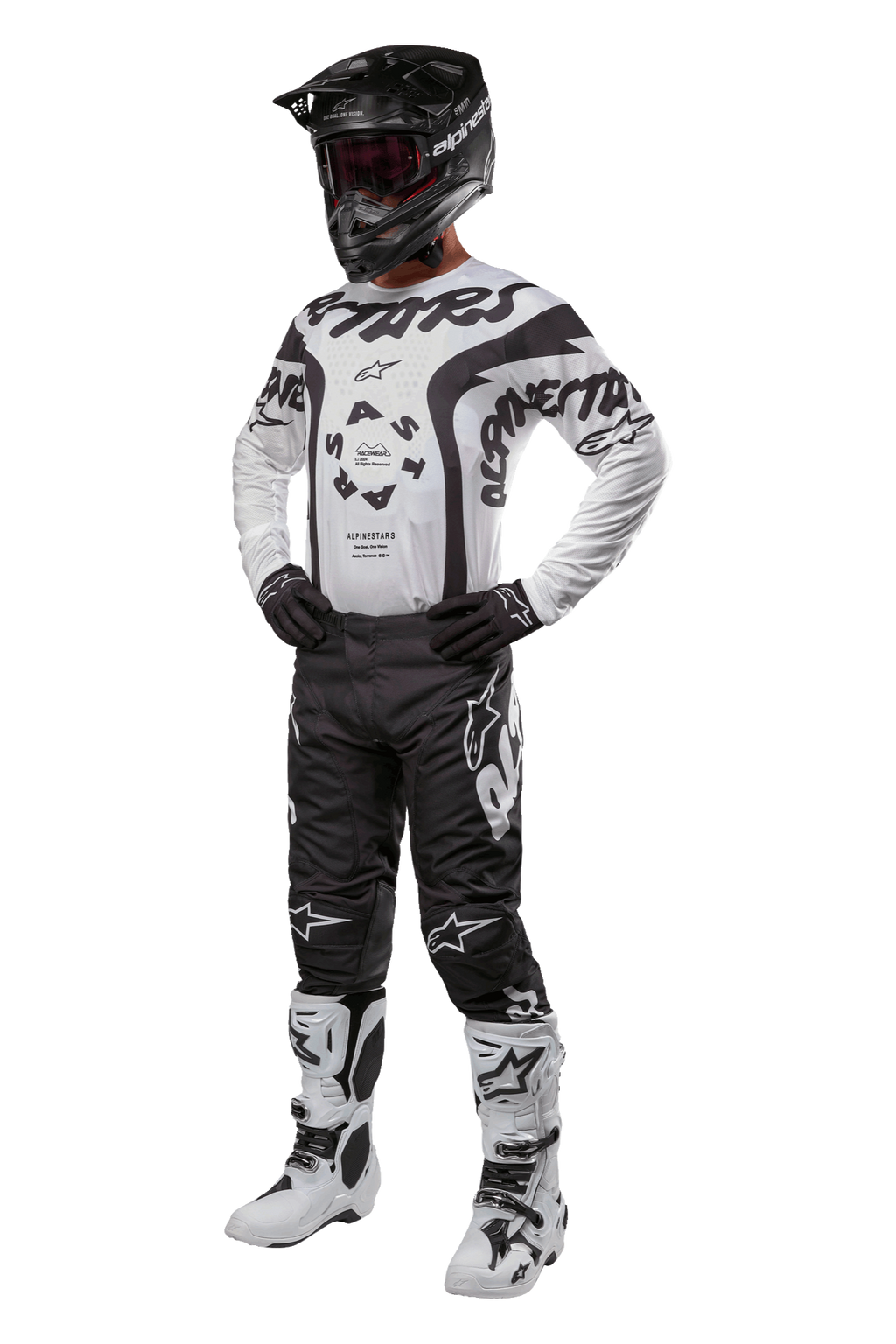 Piloto de motocross com equipamento completo, incluindo a camisola Alpinestars 2024 Racer Hana em branco e preto, calças de motocross pretas com logótipos brancos, capacete preto, botas de corrida brancas e pretas e luvas pretas, equipamento profissional de corrida off-road