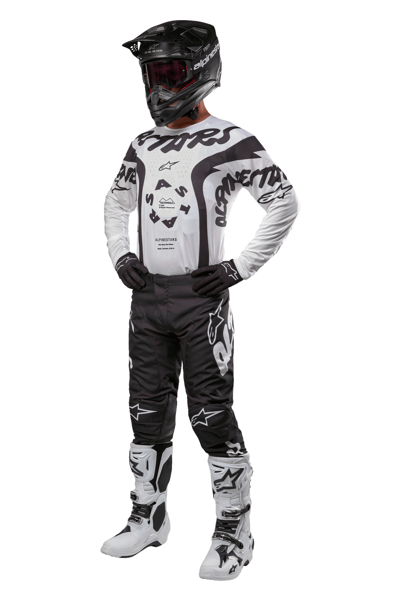 Piloto de motocross com equipamento completo, incluindo a camisola Alpinestars 2024 Racer Hana em branco e preto, calças de motocross pretas com logótipos brancos, capacete preto, botas de corrida brancas e pretas e luvas pretas, equipamento profissional de corrida off-road