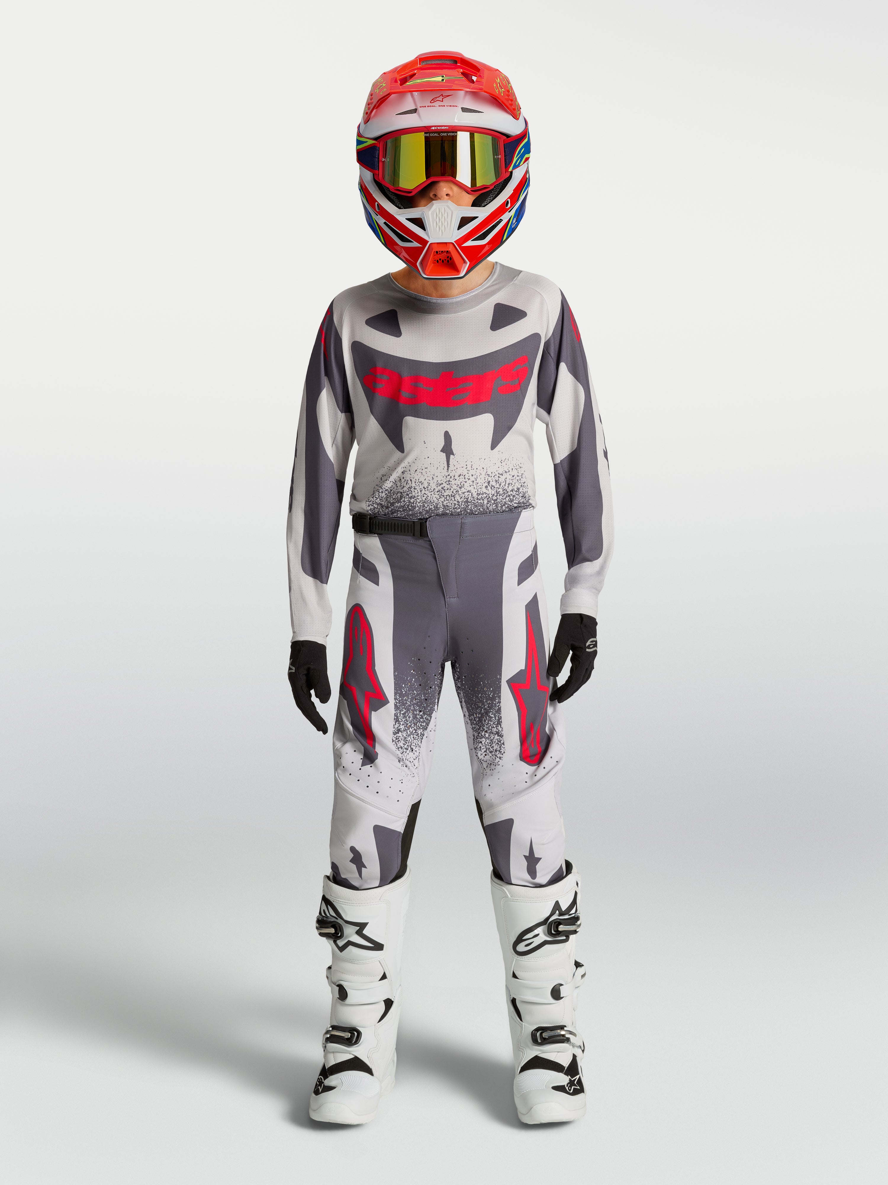 Alpinestars Supertech Swan 2027 para jovens, conjunto de motocross cinzento e branco com pormenores vermelhos.