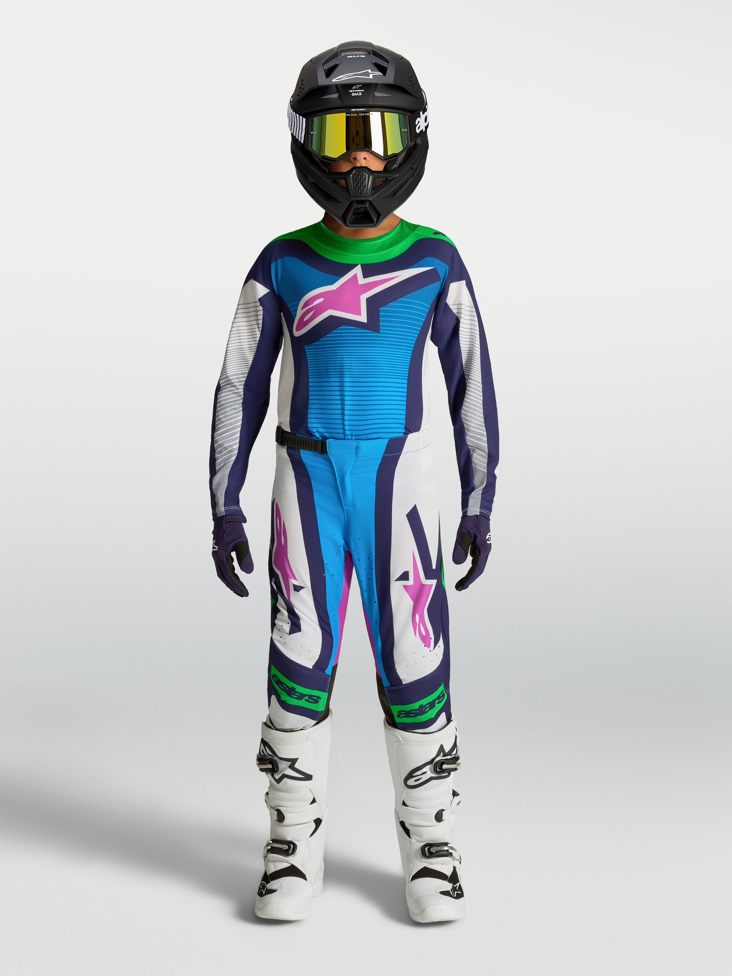 Alpinestars Juventude Supertech Maven Gear Set, conjunto de motocross azul e branco com detalhes rosa e verde, em modelo.