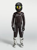 Alpinestars Camisola Fluid Apex V2 Jovem e Juventude Fluid Apex V2 Gear Set, conjunto MX preto e prateado com botas brancas.