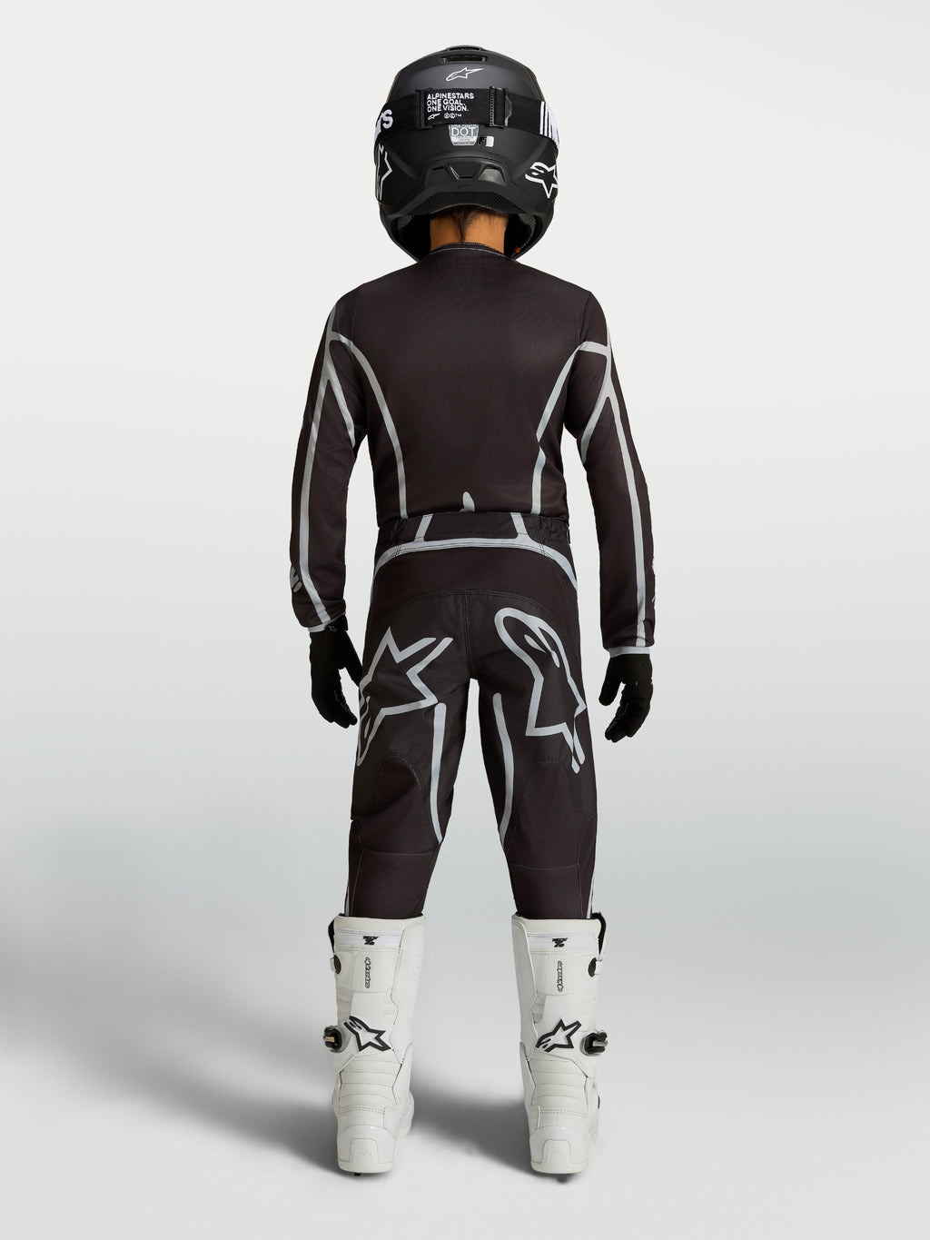 Alpinestars camisola e conjunto juventude Fluid Apex V2, kit de motocross preto e prateado com botas brancas, vista traseira.