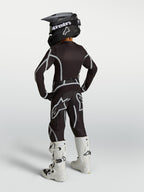 Conjunto Alpinestars 2027 Juventude Fluid Apex V2 de motocross, preto e prateado, vista traseira com botas brancas.