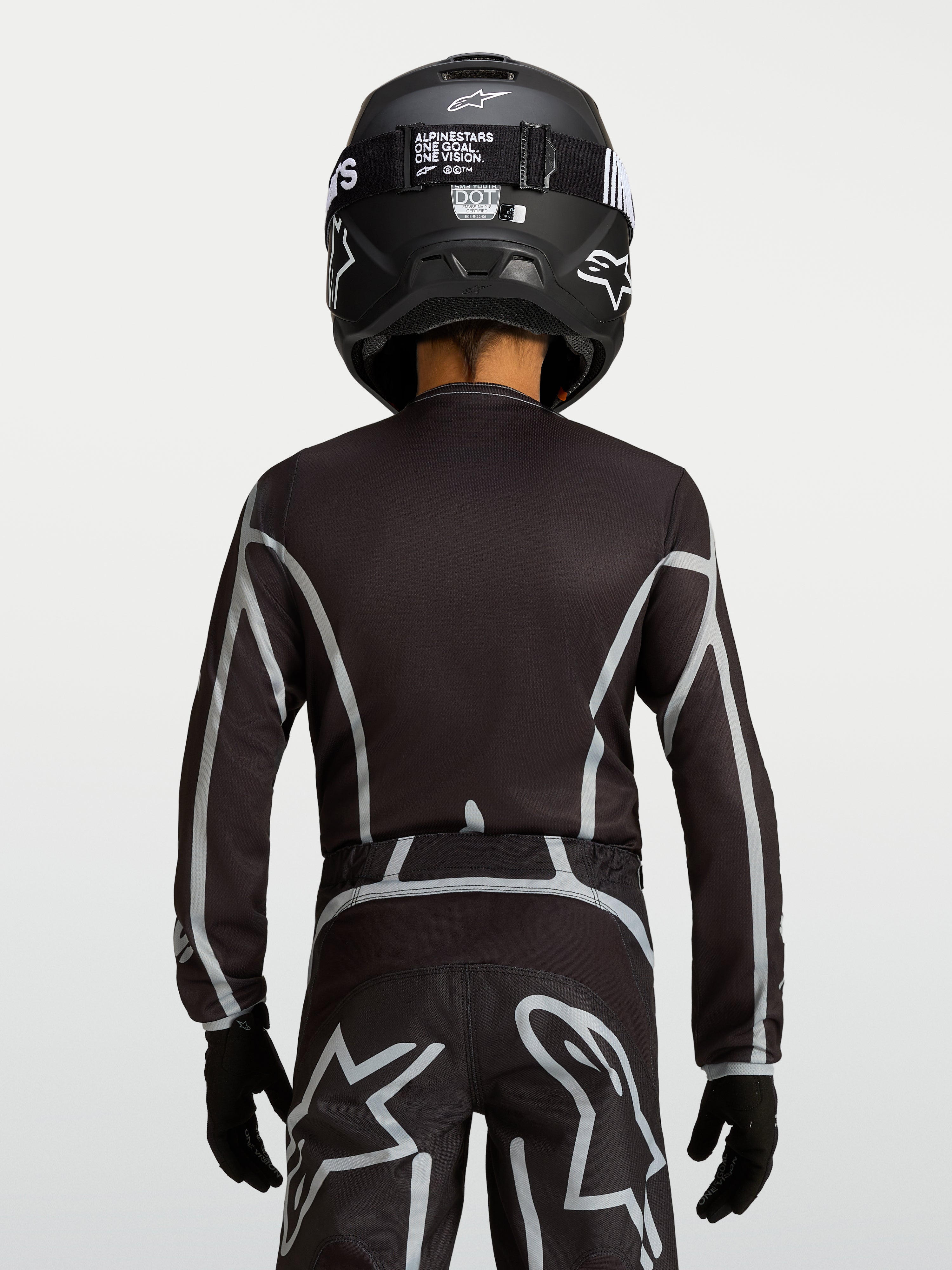 Camisola Alpinestars Fluid Apex V2 Jovem, camisola de motocross preta e prateada, vista traseira com ajuste ergonómico e cobertura traseira estendida