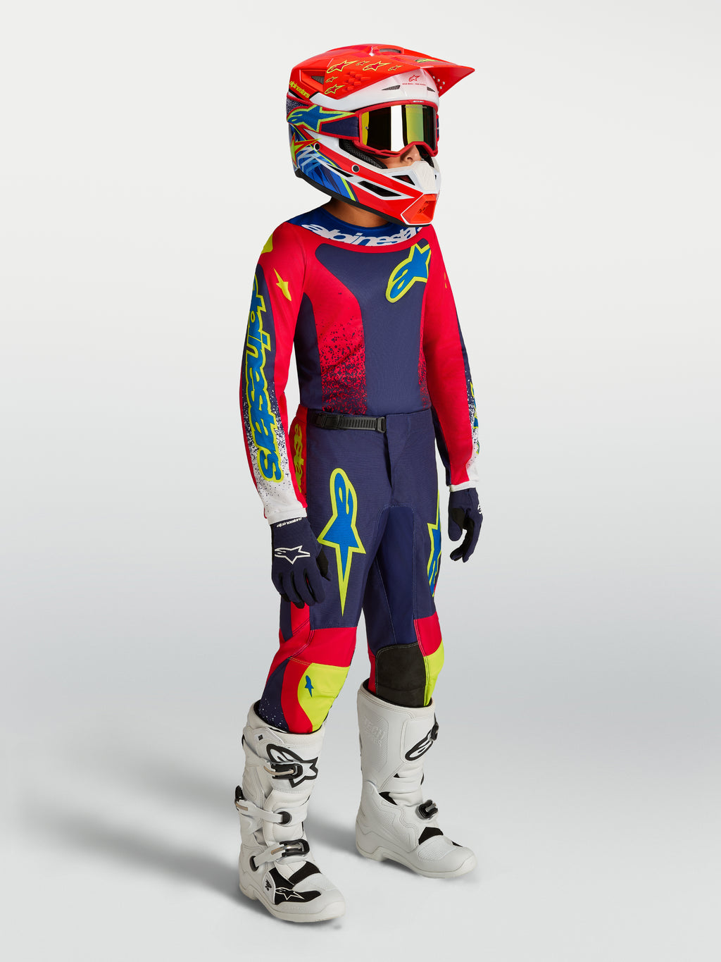 Alpinestars Juventude Fluid Drag Gear Set 2027, conjunto de motocross azul marinho e vermelho vivo com botas brancas.