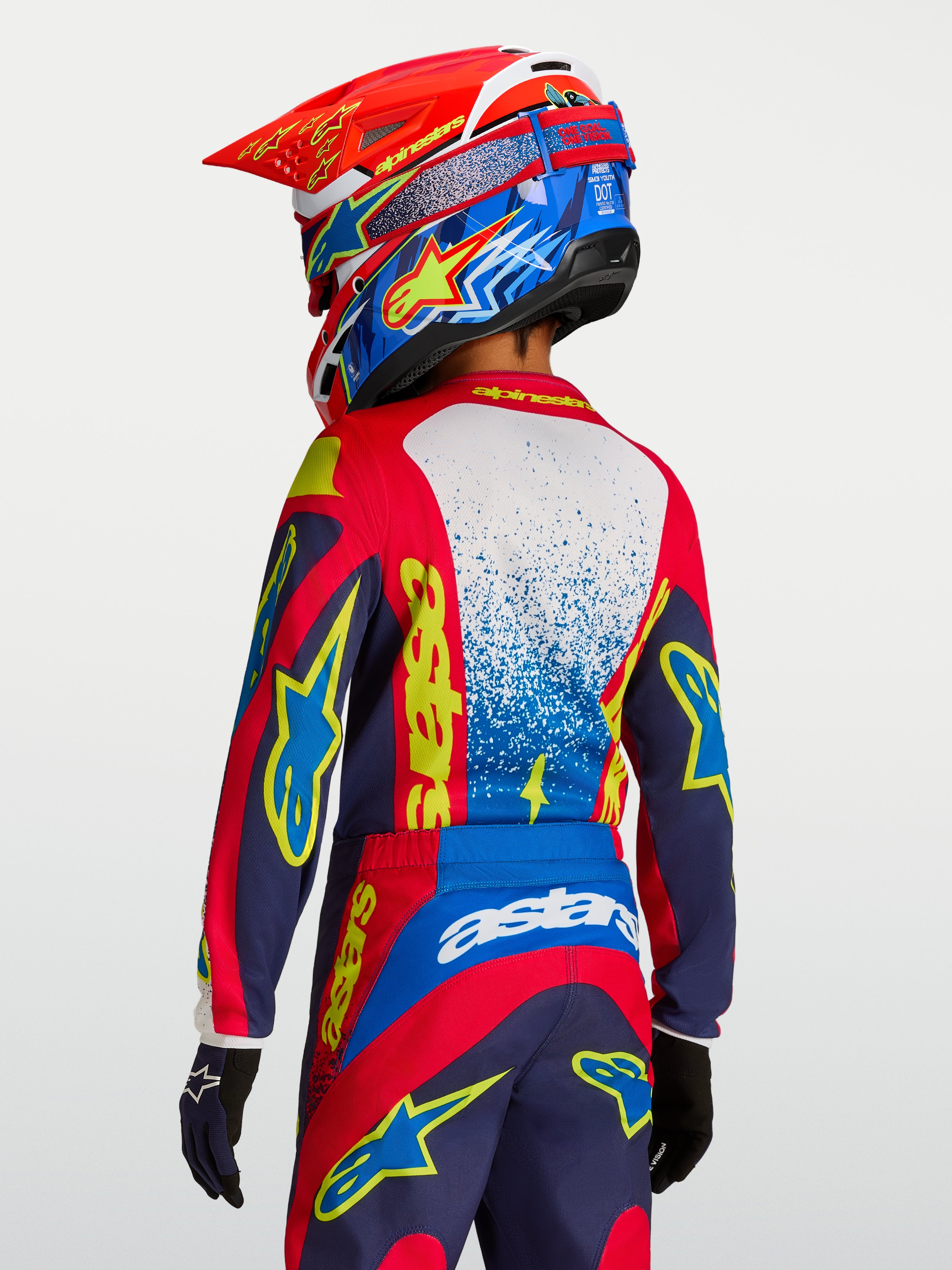 Alpinestars Fluid Drag, camisola de motocross para jovens, vermelha e azul-marinho com grafismos amarelos, vista traseira.