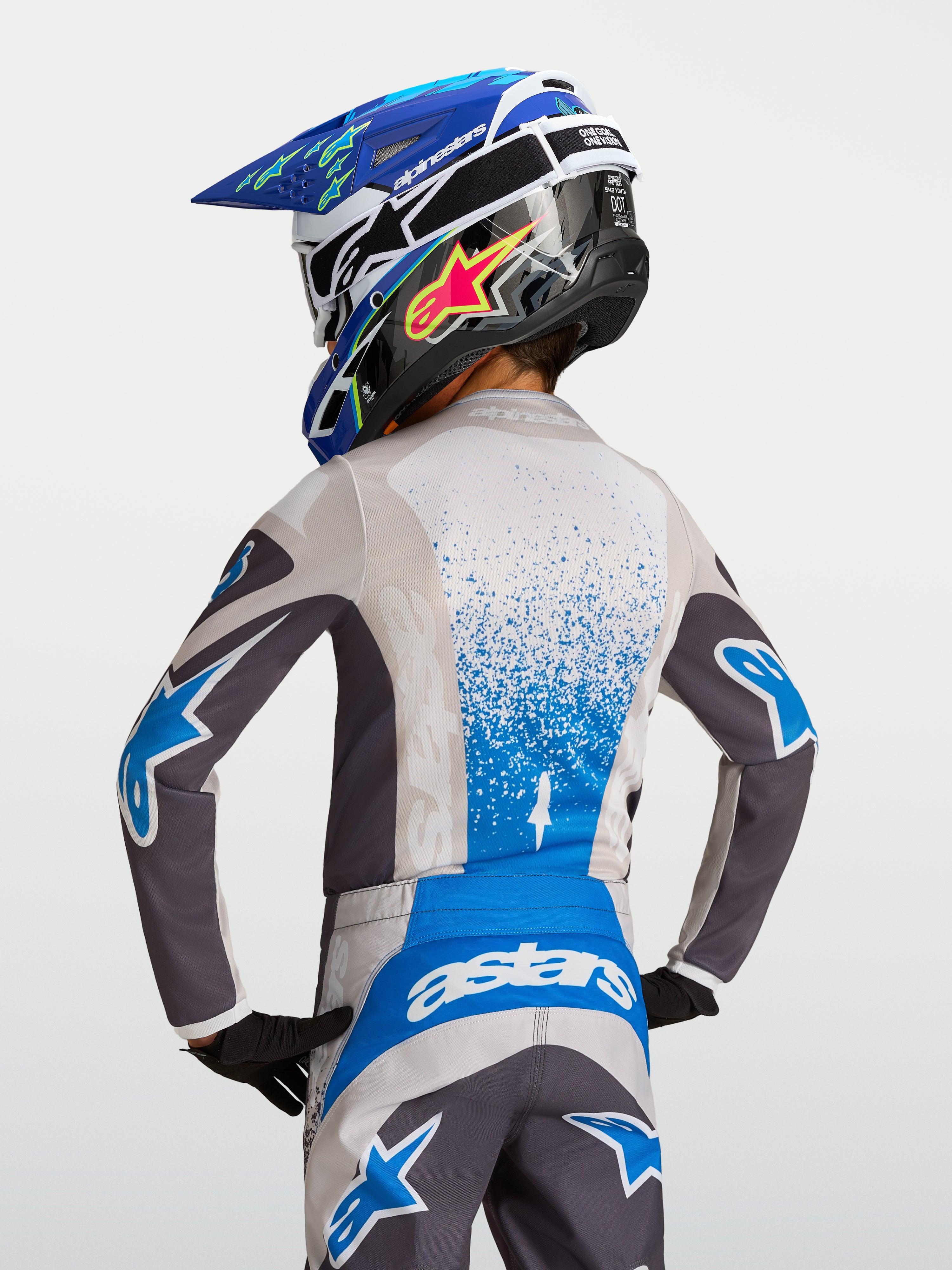 Alpinestars Camisola Fluid Drag Jovem 2027, para motocross, cinzenta e azul, vista traseira, tecido respirável.