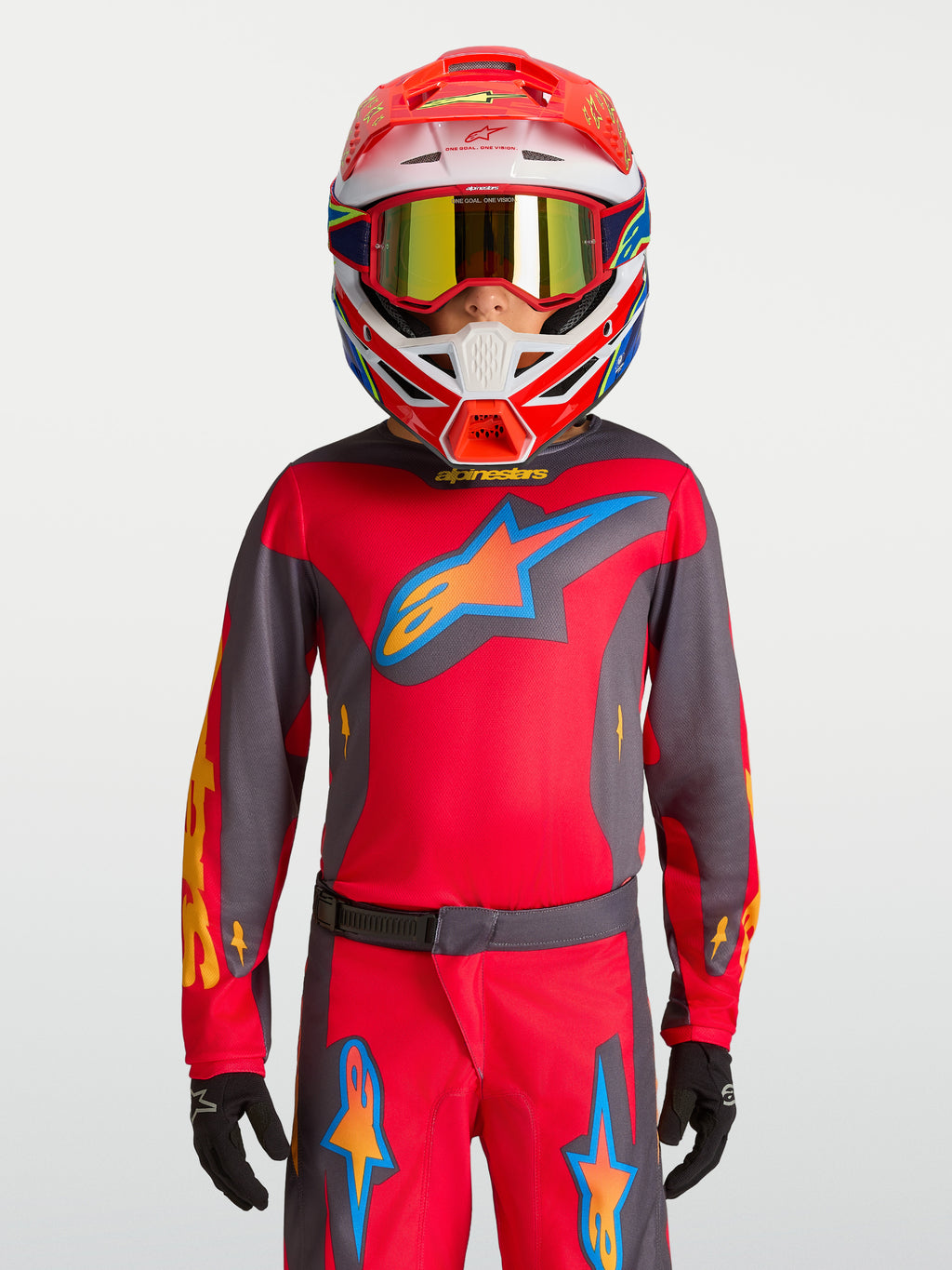 Alpinestars camisola Fluid Hunt Juventude 2027, camisola de motocross vermelha e cinzenta, no modelo com capacete de corrida.