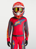 Alpinestars camisola Fluid Hunt Juventude 2027, camisola de motocross vermelha e cinzenta, no modelo com capacete de corrida.