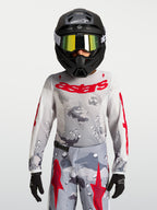 Alpinestars Camisola Fluid Lone Jovem 2027, camisola de motocross para jovens, cinzenta com padrão de camuflagem e logótipo em vermelho, construção em politecido leve e respirável.