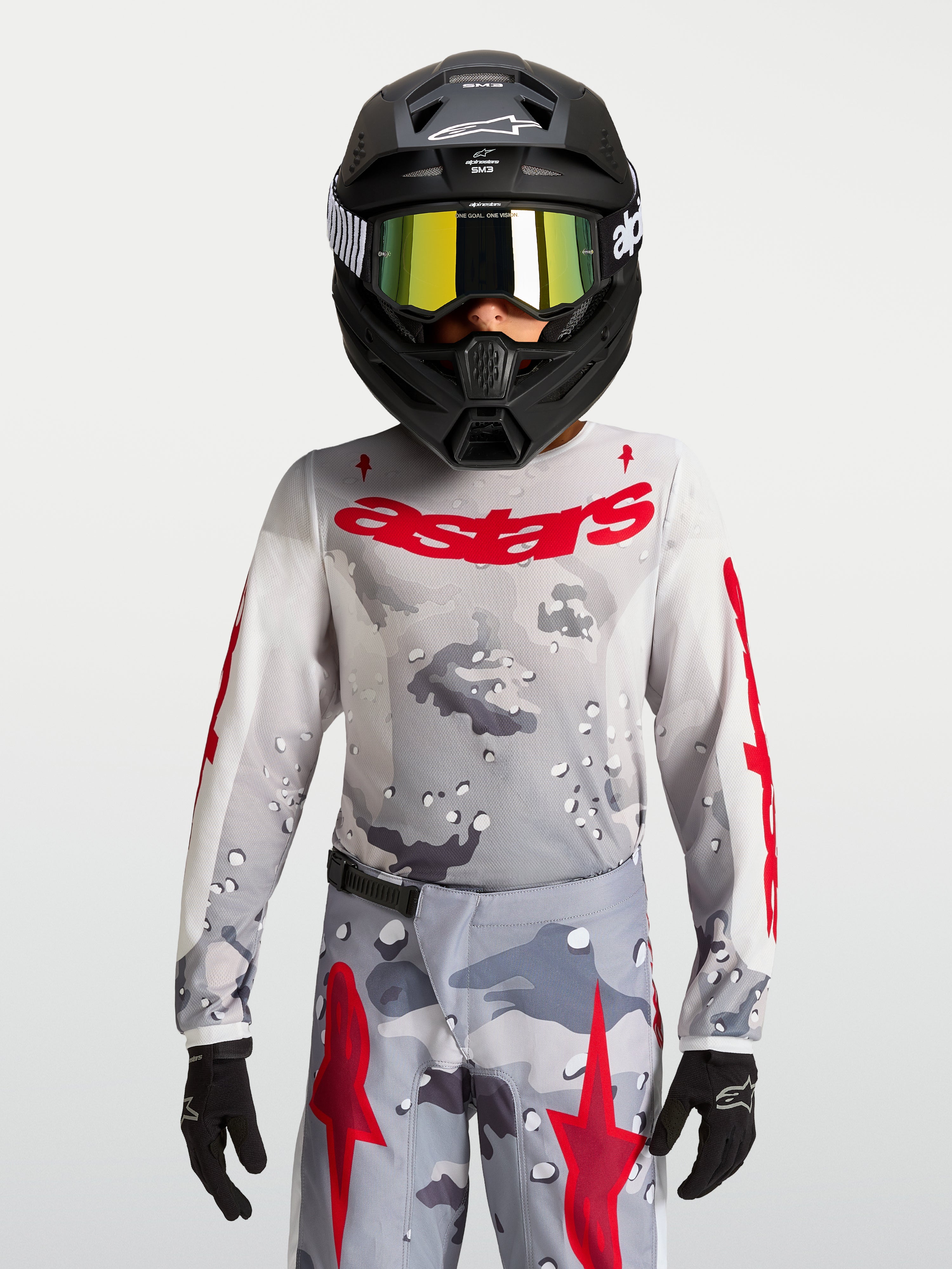 Alpinestars Camisola Fluid Lone Jovem 2027, camisola de motocross para jovens, cinzenta com padrão de camuflagem e logótipo em vermelho, construção em politecido leve e respirável.