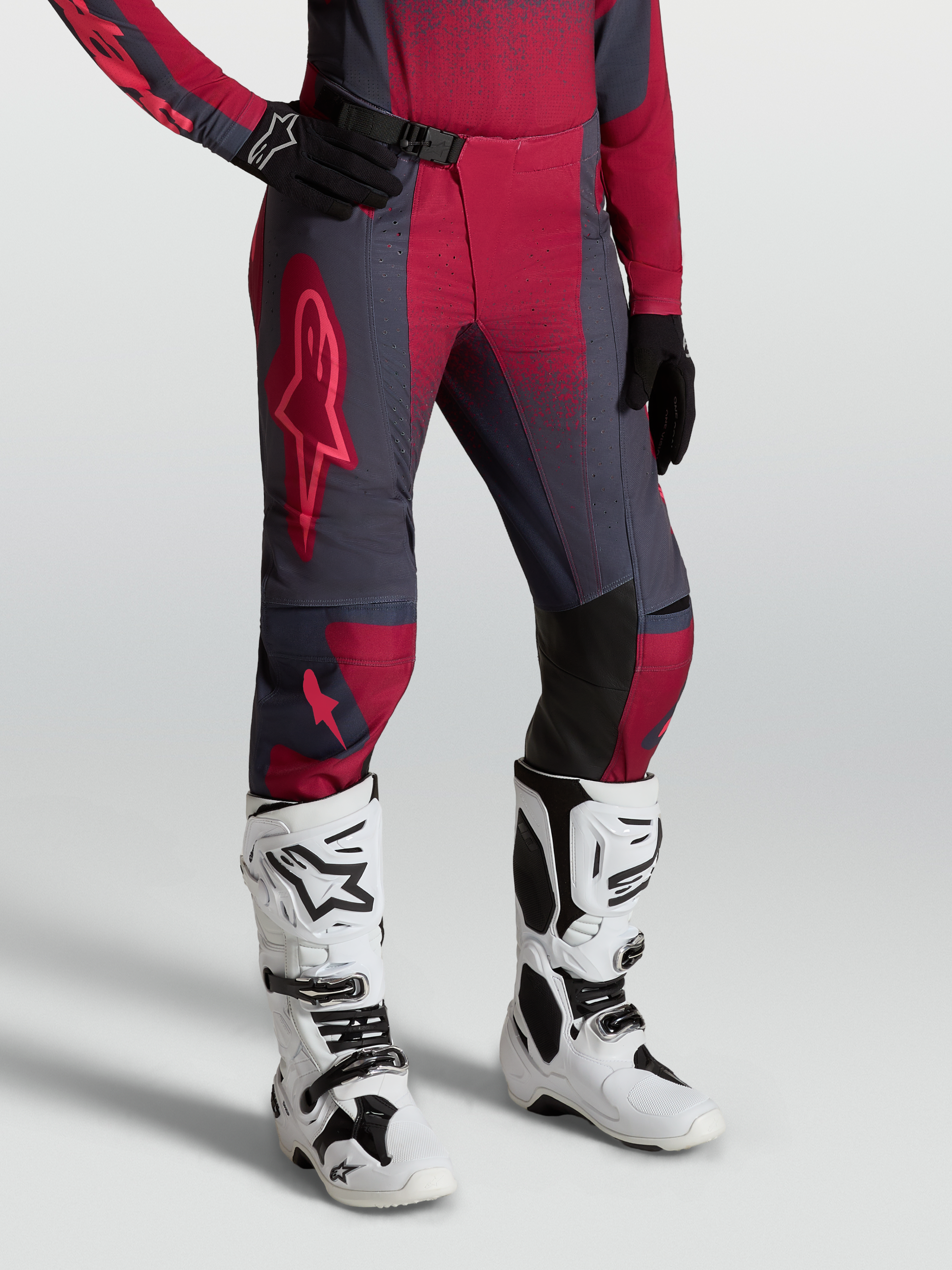 Alpinestars calças Stella Techstar Swan para mulher, motocross, carmesim e cinzento escuro, com botas Tech 10 brancas.