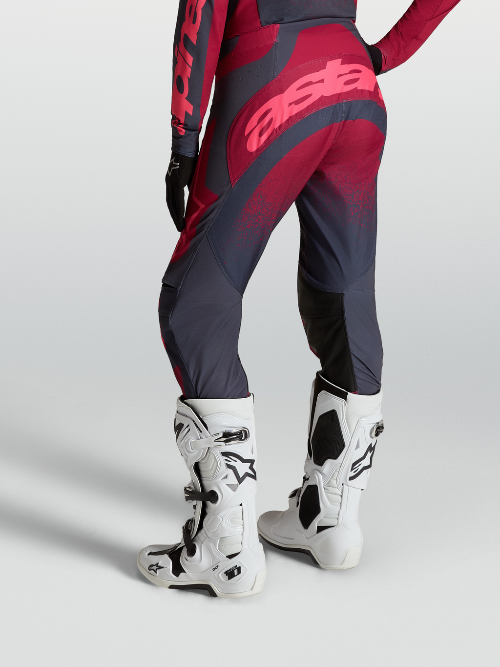 Alpinestars Stella Techstar Swan, calças de motocross para mulher, carmesim e cinzento escuro, com botas Tech 10 brancas.