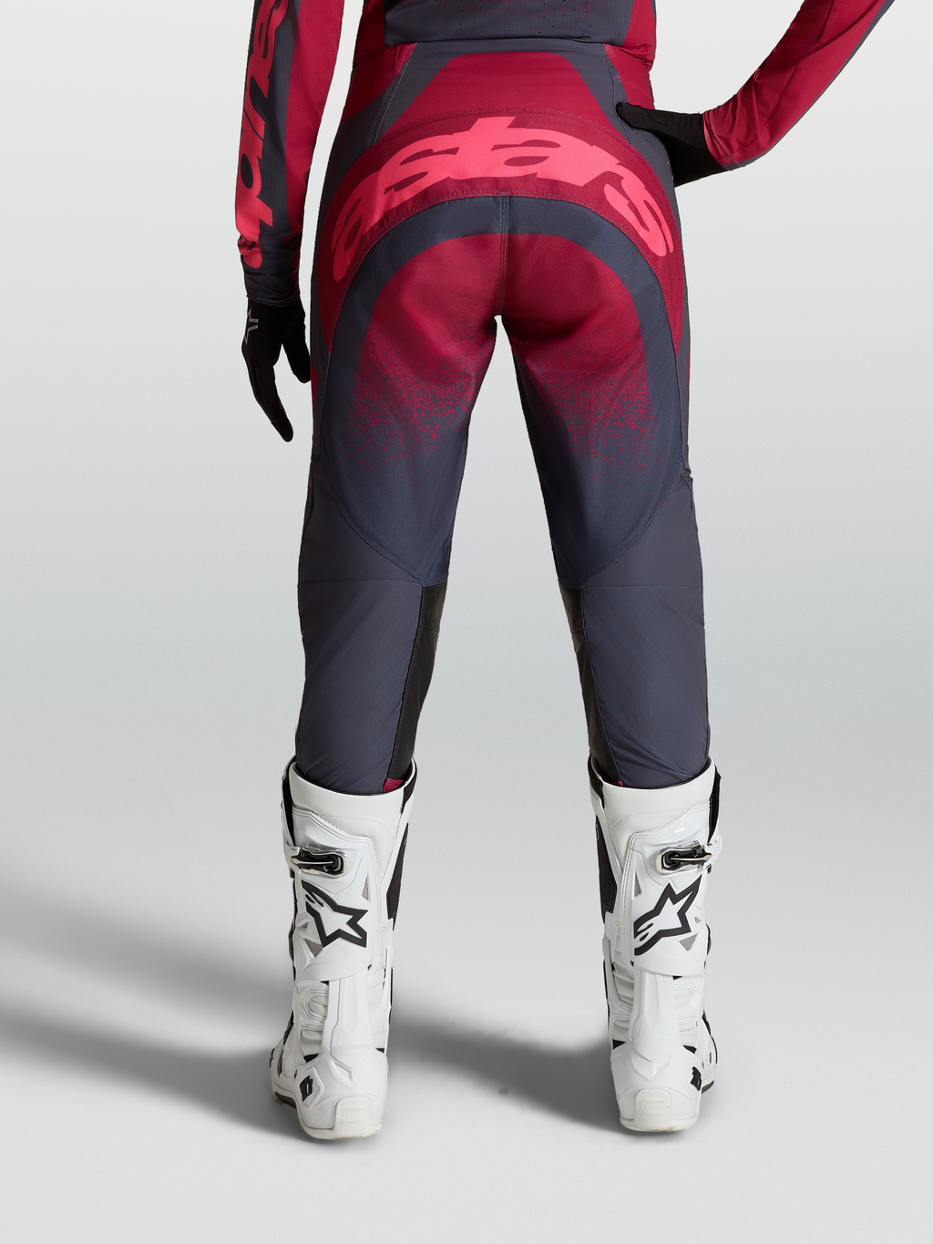 Alpinestars Calças Stella Techstar Swan, equipamento de motocross para mulher, vermelho e cinzento, vista traseira com botas de corrida brancas.