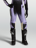 Alpinestars Stella Techstar Swan, calças de motocross para mulher, roxo claro e preto com pormenores em pele creme, combinadas com botas off-road pretas.