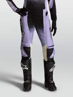 Alpinestars Stella Techstar Swan, calças de motocross para mulher, roxo claro e preto com pormenores em pele creme, combinadas com botas off-road pretas.
