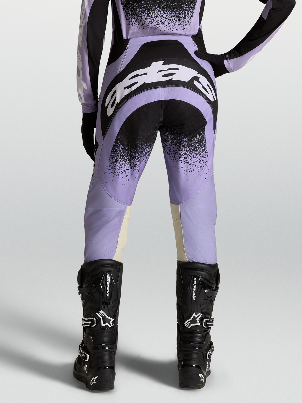 Alpinestars Calças Stella Techstar Swan, equipamento de motocross para mulher, roxas e pretas, vista traseira com botas pretas.