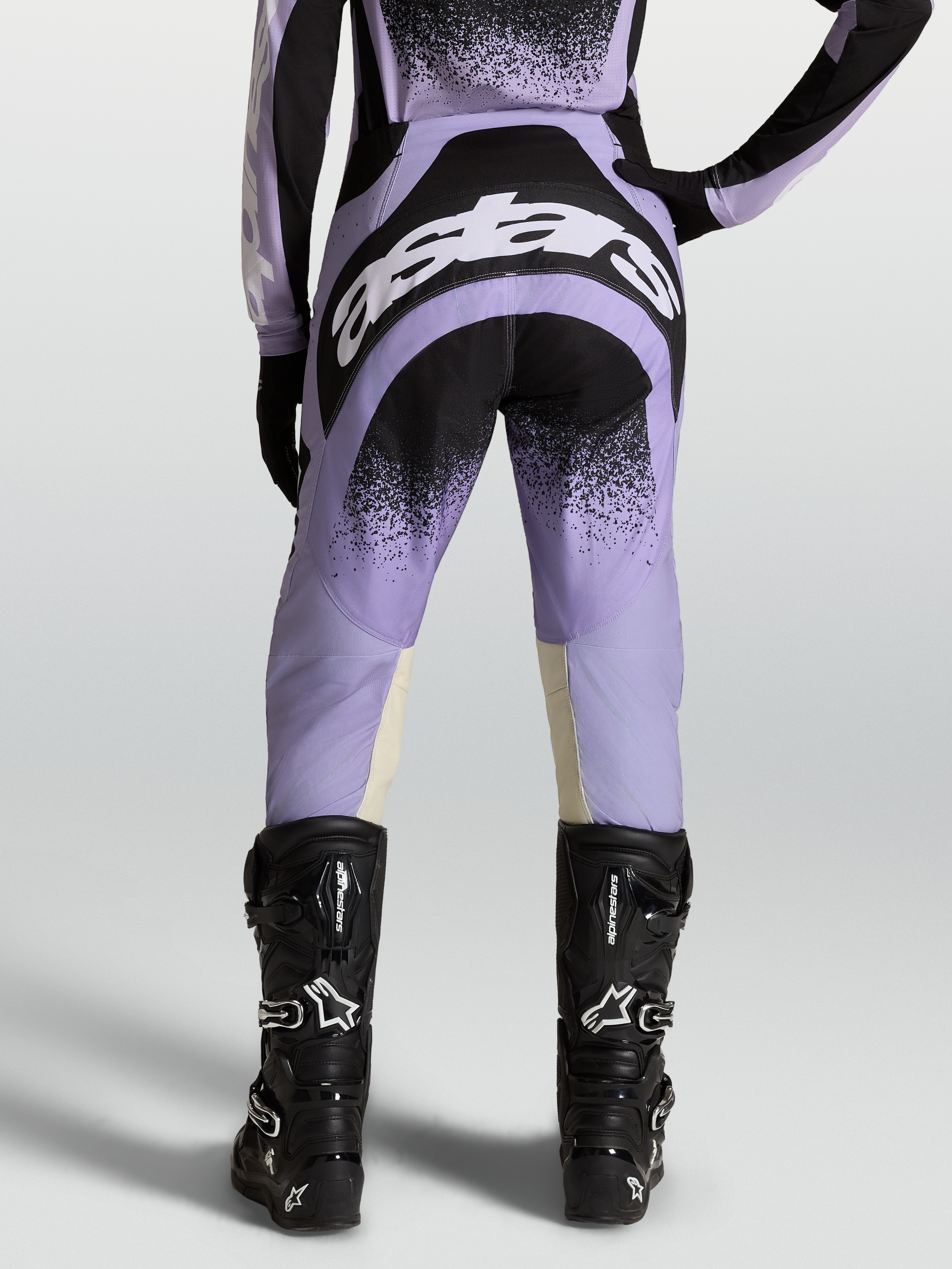 Alpinestars Calças Stella Techstar Swan, equipamento de motocross para mulher, roxas e pretas, vista traseira com botas pretas.