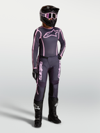 Alpinestars Stella Fluid Apex V2, conjunto de motocross para mulher, cinzento e rosa, com botas de moto pretas e capacete.