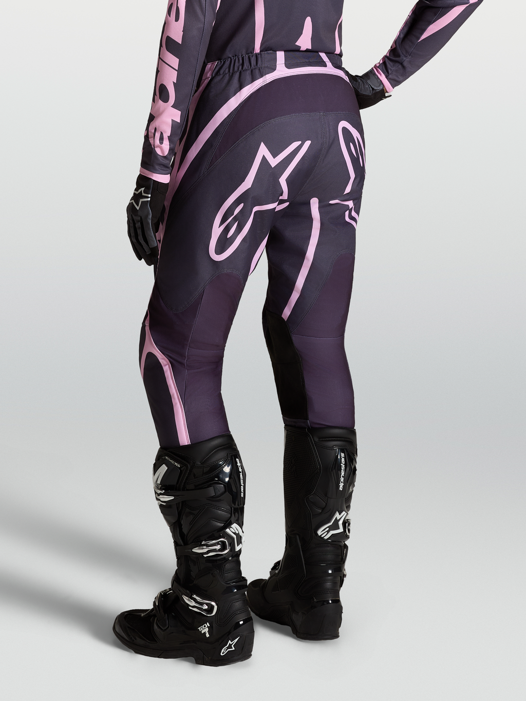 Alpinestars Stella Fluid Apex V2, calças de motocross para mulher, cinzentas e rosa, combinadas com botas Tech 7 pretas.
