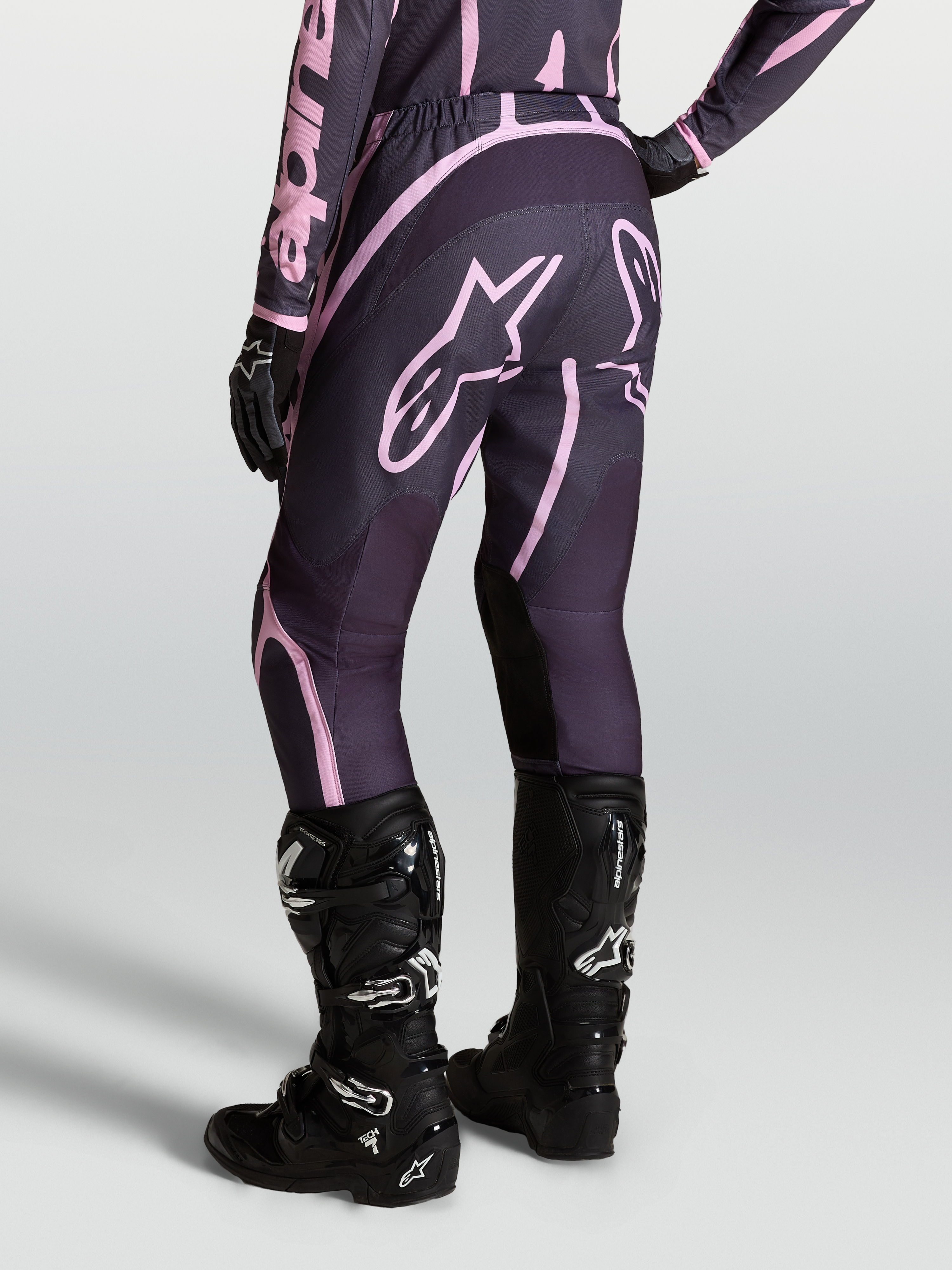 Alpinestars Stella Fluid Apex V2, calças de motocross para mulher, cinzentas e rosa, combinadas com botas Tech 7 pretas.